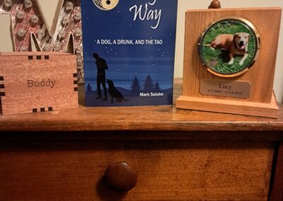 Lucy’s Way book displayed beside urns holding the ashes of Lucy and Buddy Saluke
