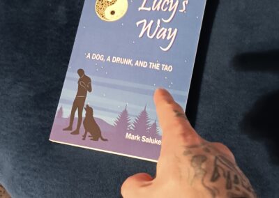 Person pointing at their copy of Lucy’s Way by Mark Saluke