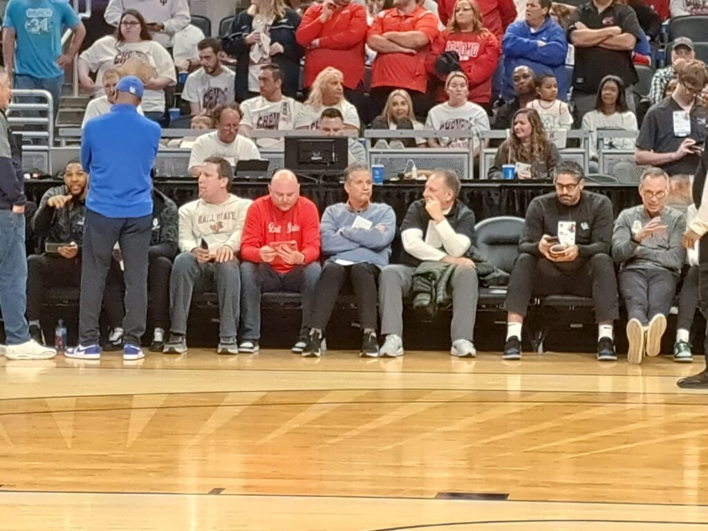 Ball State coach Mike Lewis, Kentucky coach John Calipari, and Michigan State coach Tom Izzo sitting courtside watching Flory Bidunga at the 2023 Indiana High School boys basketball State Finals at Gainbridge Fieldhouse.